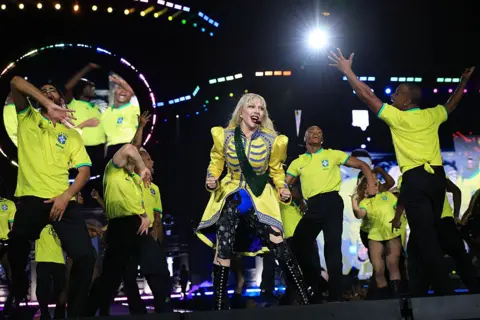 Getty Images Lady Gaga dances in a yellow jacket with dances in yellow t-shirts