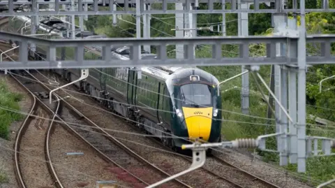 A green and yellow GWR train on the tracks near to Cardiff Central station
