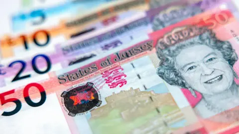 A close up image of various Jersey banknotes featuring Queen Elizabeth II. 