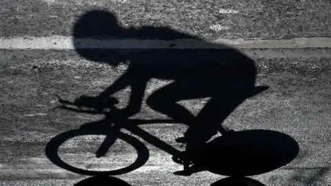 The shadow of a rider who is competing in a professional cycling race