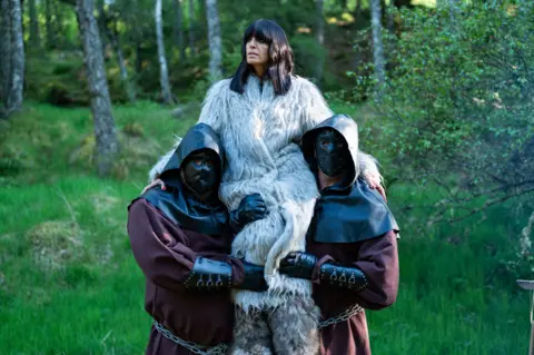 Claudia Winklemen being held up   successful  the aerial  by 2  assistants portion    filming The Traitors