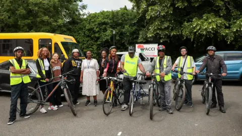 ACCI A row of men and women, some are holding bikes and some are wearing high-vis jackets.