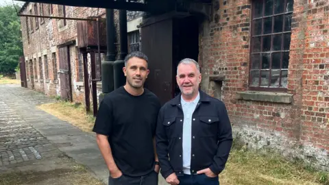 David Spereall/BBC The two men previously pictured above stood in front of the old brick building.