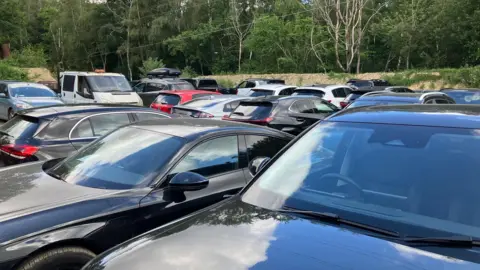 Piers Hopkirk/BBC Rows of cars parked near a scrapyard. 