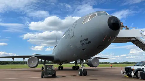 McDonnell Douglas KC-10 Extender a grey aircraft with black tip on its front it is a large craft on an airport runway