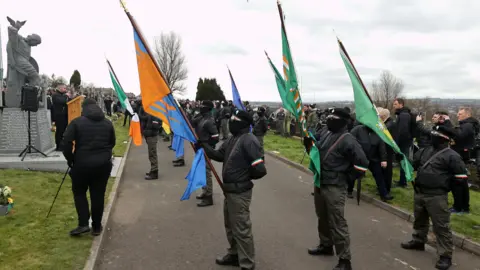 Liam McBurney/PA Wire Masked men in paramilitary-style uniforms lead the march through Creggan to the city cemetery