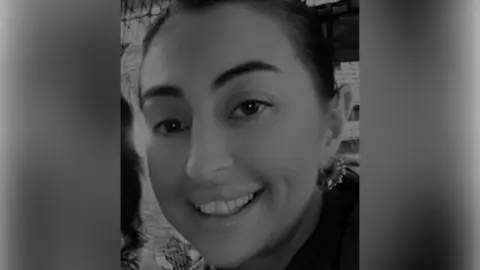 Family A black and white picture of a smiling woman with tied-back dark hair and earrings.