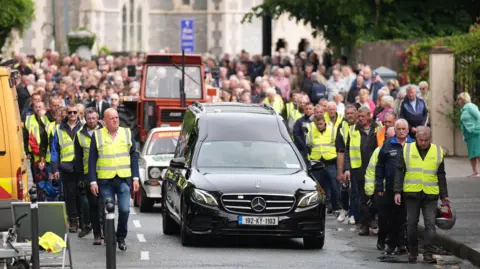 Niall Carson/PA Wire The hearse leaving following the funeral of murdered Co Kerry farmer Michael Gaine at the Holy Cross Church in Kenmare. Picture date: Saturday June 7, 2025. PA Photo. See PA story FUNERAL Gaine. Photo credit should read: Niall Carson/PA Wire