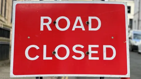 A closeup of a red sign that has Road Closed written on it in white letters.