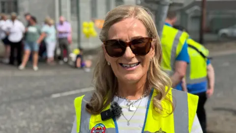 Frances Barrett is wearing big sunglasses and a hi vis vest