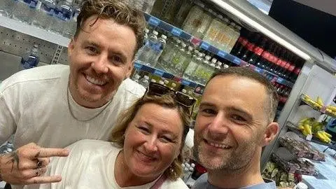 Clare Cersuolo Clare who has short blonde hair smiling at the camera between Danny Jones and Harry Judd from McFly