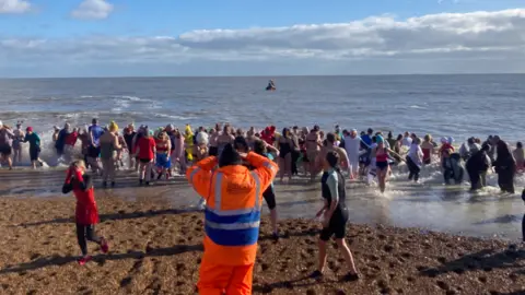 Members of the public can be seen getting into the sea on the beach.