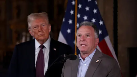 Reuters De nieuwgekozen Amerikaanse president Donald Trump (L) kijkt toe terwijl zijn Midden-Oostengezant Steve Witkoff (R) spreekt op een persconferentie in Mar-a-Lago, Florida, VS (7 januari 2025)