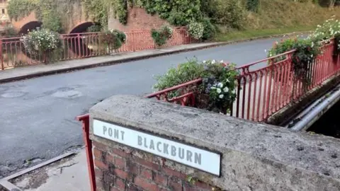 View of the bridge over the Somme river in Peronne with a sign saying "Pont Blackburn" in the foreground.  