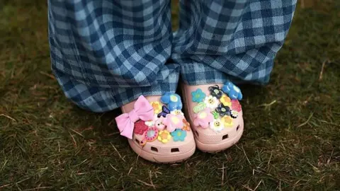 Getty Images Woman wears pink Croc clogs, adorned with different coloured charms
