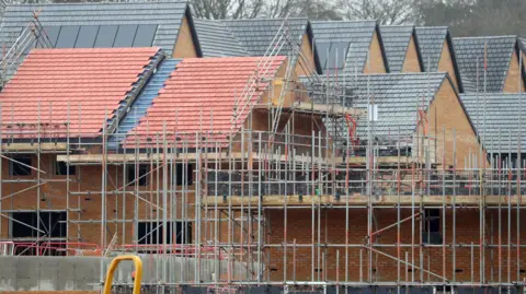 PA Media New homes under construction. There are three homes central to the image with scaffolding around them.