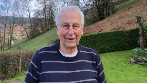 Stuart Davies Stuart Davies is wearing a navy jumper and looking straight ahead at the camera. 