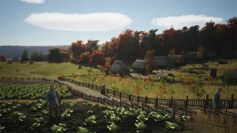 This Slavic Magic screenshot shows a pastoral scene depicting a medieval settlement. In the foreground, a farm worker tends to crops arranged in rows. Behind, there are trees in a fenced area and the path leads to a row of small thatched dwellings. Other workers wear old factory clothes around the landscape that stretches into the distance.