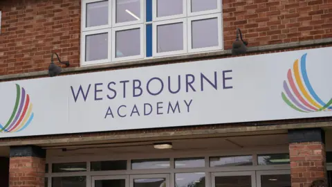 Shaun Whitmore/BBC A large white sign with WESTBOURNE ACADEMY written on it. It is fixed to the entrance of a school building.
