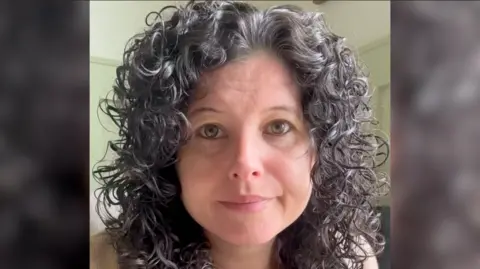 Facebook A woman with black curly shoulder length hair looks directly into the camera.