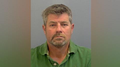 Jason Briars wearing a green polo shirt in custody