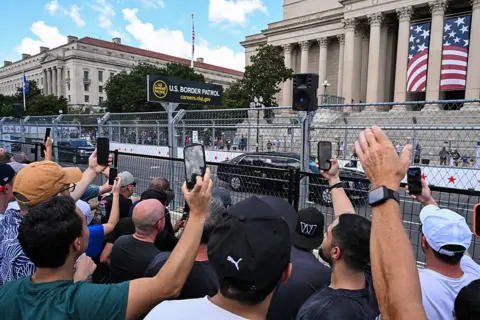 Getty Images People hold up their phones to capture The Beast through the streets