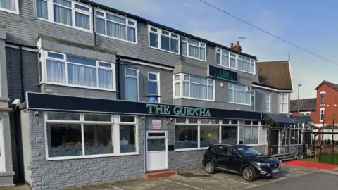 Google The Gurkha restaurant, which is in a three story terraced building painted grey with a green sign