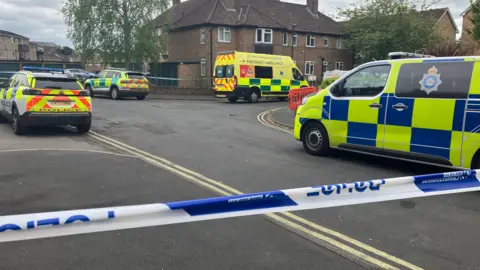 BBC/ Jack Hadaway-Weller Police vans, cars and ambulances in a cordoned off residential street.