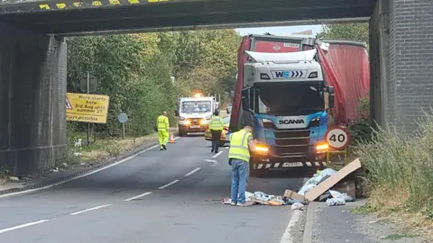 Hinckley Town Centre A man stands in front of a damaged lorry that has crashed into the bridge. 