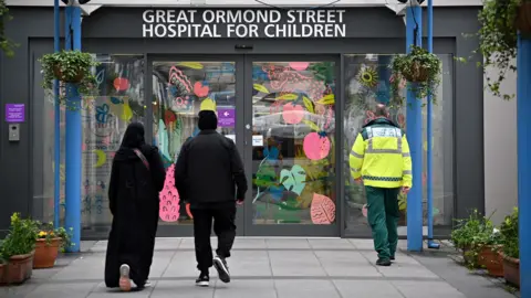 People walk under a sign for Great Ormond Street Hospital at its entrance