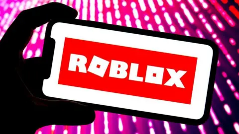 Getty Images Silhouette of a mobile phone with the Roblox branding on the screen. 