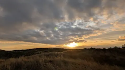 ALIDEAKIN/WEATHERWATCHERS Sunshine pictured from what appears to be a cliff's edge in Winterton-on-Sea. There are clouds in the sky.