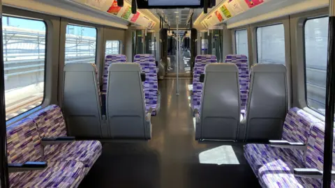 Empty carriage shows purple patterned seats with grey backs