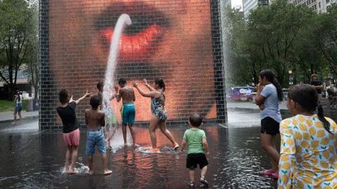 Children cool off at Crown Fountain in Millennium Park as temperatures reached a record high of 97F (36.1C) on 17 June in Chicago, Illinois