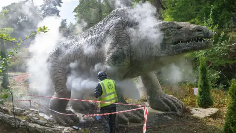 Historic England Archive The Megalosaurus being steam cleaned by someone in a high-visibility jacket.