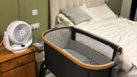 Jackson Bylett A bedroom with a bed, crib and a fan