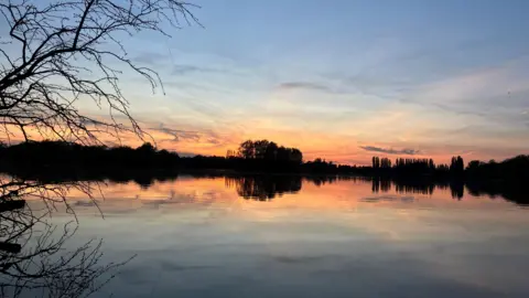 Sunset over Hardwick lakes with the sky reflected in the water, near Standlake