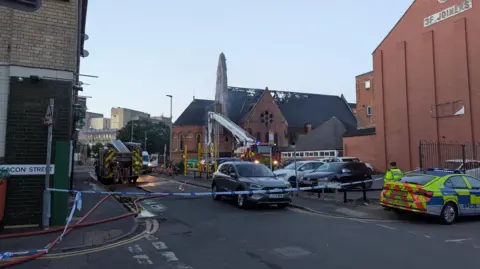 Damage to the roof of a church behind a police cordon