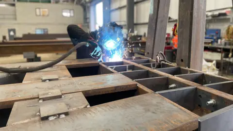 A welder works on a steel section of the Lancaster bomber sculpture