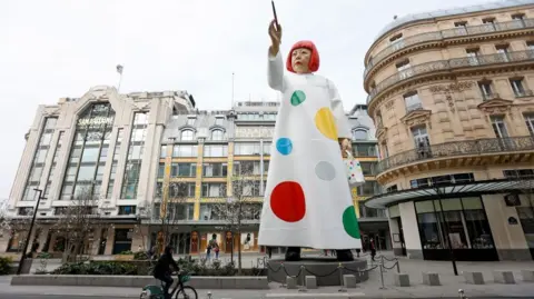 Chesnot/Getty Images A huge sculpture in the likeness of Yayoi Kusama is erected between the headquarters of the Maison Louis Vuitton and the Samaritaine department store on March 06, 2023 in Paris, France.