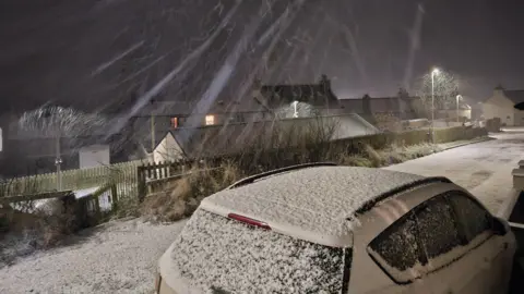 olly79/BBC Weather Watchers Streaks of snow falling caught on camera, as it covers a car and the ground