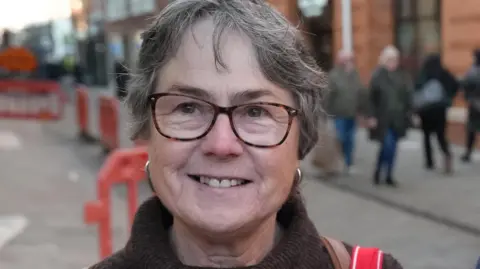 BBC/Joe Weir Kay Meyers - a woman with grey hair and glasses smiles for the camera 