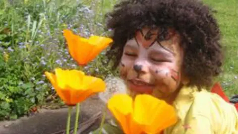 Image shows seven-year-old Zane Gbangbola with flowers in a garden