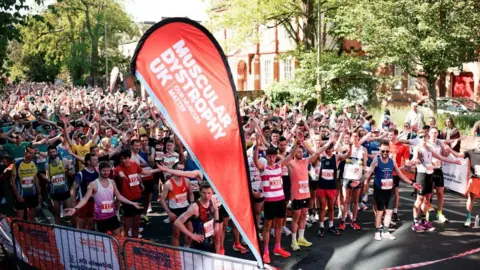 People waiting at the start line ready to take on the 10k race in Oxford. It is a sunny day.