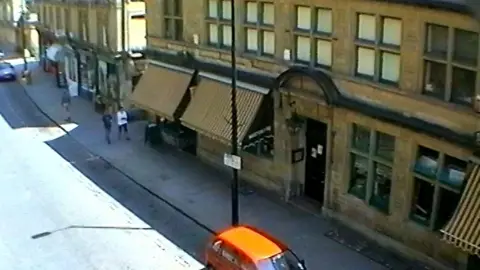 Avon and Somerset Police A CCTV image showing the outside of Cadillacs nightclub in Bath. It is a large brown building just off the main road, with striped awning and lots of windows. 