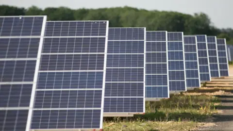 Daniel Leal-Olivas/PA Media Solar panels standing in a field