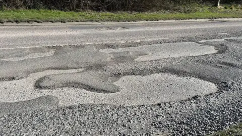 A series of large potholes next to each other on a road.