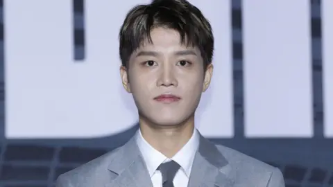 Taeil, former member of the K-pop band NCT, dressed in a gray suit, white shirt and gray tie, poses for the camera at a press conference in Seoul, in September 2022