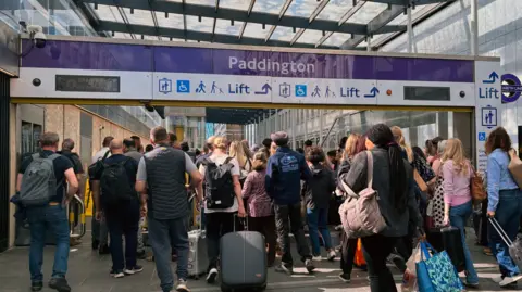 PA Media Crowd of people with luggage entering Paddington station via the Elizabeth line entrance.