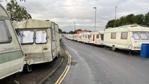 BBC A number of dirty, dilapidated caravans were parked one behind the other along the road. 